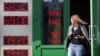 RUSSIA -- A woman leaves exchange office with an electronic panel displaying currency exchange rates for U.S. dollar and euro against Russian ruble in Moscow, August 23, 2018