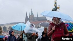 Ljudi hodaju preko srednjovjekovnog Karlovog mosta tijekom kišne oluje u Pragu, Češka , 13. 9. 2024. REUTERS