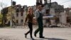 Local residents walk past a destroyed building in the Ukrainian port city of Mariupol on territory currently controlled by Russia-backed forces on April 29. .