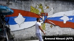 Un cetățean sârb dintr-un cartier cu majoritate sârbească din orașul Mitrovica din sudul Kosovo trece prin fața unui zid în care harta Kosovo este integrată în steagul Serbiei.