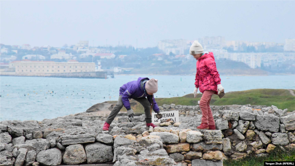 Дети играют на древних стенах, укладывая небольшие камни