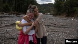 Two local woman react after floods and landslides hit the village of Trusina in Bosnia-Herzegovina. 