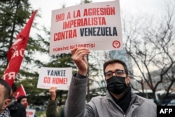 Акцыя пратэсту прадстаўнікоў Рабочай партыі Турэччыны каля амбасады ЗША ў Анкары. Адзін з удзельнікаў трымае плякат з надпісам «Не імпэрыялістычнай агрэсіі супраць Вэнэсуэлы».