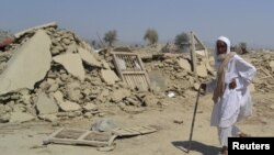 A survivor of the earthquake in Balochistan walks near the rubble of a mud house that collapsed during the temblor. 