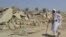 A survivor of the earthquake in Balochistan walks near the rubble of a mud house that collapsed during the temblor. 