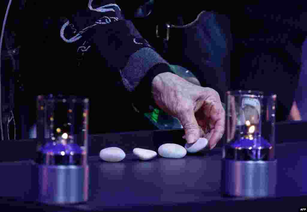 Un supraviețuitor al Holocaustului depune pietre între lumânări. Obiceiul ebraic de a pune o piatră pe un mormânt este străvechi. &bdquo;Prin acest lucru, adăugăm simbolic piatra funerară, construind memorialul care-l onorează pe decedat&rdquo; (Sorin Gold). La Auschwitz Birkenau, evreii au fost gazați și apoi arși. Ei nu au morminte -&nbsp;Oswiecim, Polonia.&nbsp;