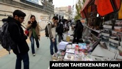 Iranians look at newspapers displayed on the ground outside a kiosk in a street of Tehran, Iran, 24 November 2013.