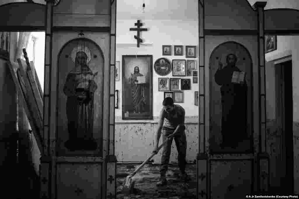 Photographer Alexander Zemlianichenko Jr. of Russia was selected for this image of a soldier cleaning mud and silt from inside a church in the village of Nizhnebakanskaya near Krymsk, Russia.