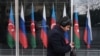 Озарбайжон ва Россия байроқлари олдидан ўтиб кетаётган шахс. Расм иллютрация учун ишлатилди. 