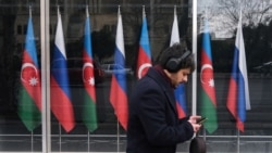 Озарбайжон ва Россия байроқлари олдидан ўтиб кетаётган шахс. Расм иллютрация учун ишлатилди. 