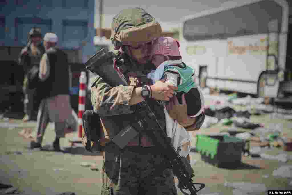 A U.S. Marine carries a baby as an Afghan family is processed at an evacuation center at Hamid Karzai International Airport in Kabul. &nbsp;
