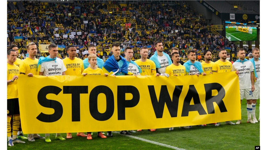 Jucătorii Borussiei Dortmund și echipei ucrainene Dinamo Kiev înaintea unui meci din Liga Campionilor din aprilie 2022, pe stadionul din orașul german, cu mesajul „Opriți războiul”.