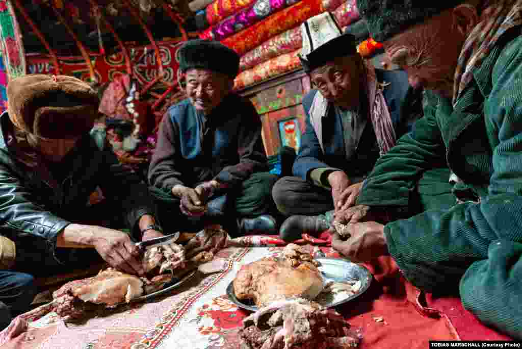 A feast with clan elders inside a yurt at the Qurbon Ait settlement in the Pamirs. Small pieces of liver are dipped with meat from fat-tail sheep into salt water after a round of tea with milk and broth. 