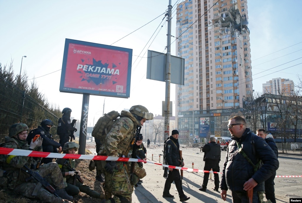 Ushtarët ukrainas shihen pranë një kompleksi banesor në Kiev, të dëmtuar nga granatimet.   