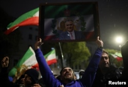 აქციის მონაწილე რეზა ფეჰლევის პორტრეტით. დიდი ბრიტანეთი