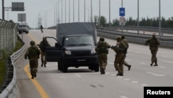Мъже с военни униформи обкръжават превозно средство на магистралата към Москва. Предполага се, че са наемници от "Вагнер"