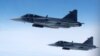 Swedish Air Force Saab JAS 39 Gripen fighter jets fly alongside an aircraft simulating aerial interceptions during a NATO media day on July 4.