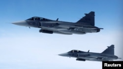 Swedish Air Force Saab JAS 39 Gripen fighter jets fly alongside an aircraft simulating aerial interceptions during a NATO media day on July 4.