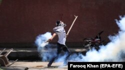 FILE: A Kashmiri student throws back a tear smoke shell at Indian police personnel during clashes in Srinagar, the summer capital of Indian Kashmir on May 14.