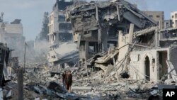 Palestinci hodaju kroz ruševine zgrada uništenih izraelskim zračnim napadima u Gazi, 10. oktobar 2023. godine.