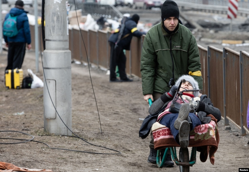 Ukrainë: Një grua duke u transportuar me karrocë, në mes të njerëzve që i ikën sulmeve ruse në Irpin, afër Kievit më 9 mars 2022.