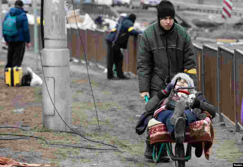 Kosovë: Një grup shqiptarësh pasi arritën në këmbë nga Peja në kufirin me Malin e Zi më 30 mars 1999.Ukrainë: Një grua duke u transportuar me karrocë, në mes të njerëzve që i ikën sulmeve ruse në Irpin, afër Kievit më 9 mars 2022.