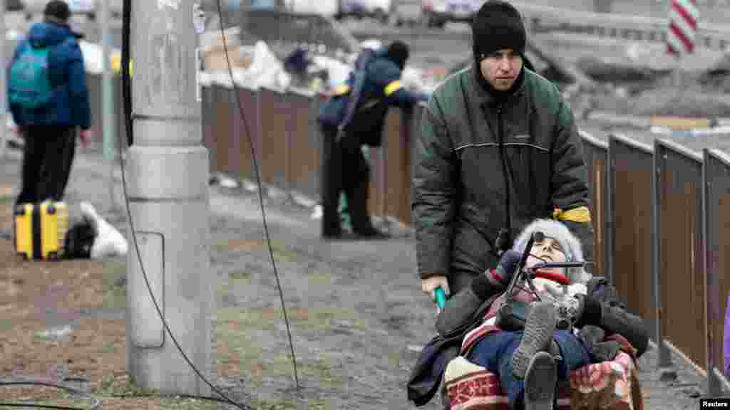 Kosovë: Një grup shqiptarësh pasi arritën në këmbë nga Peja në kufirin me Malin e Zi më 30 mars 1999.Ukrainë: Një grua duke u transportuar me karrocë, në mes të njerëzve që i ikën sulmeve ruse në Irpin, afër Kievit më 9 mars 2022.