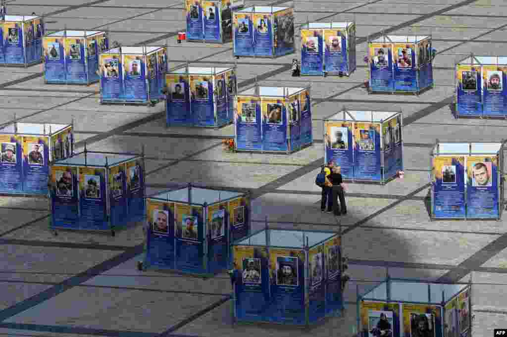 A couple looks at posters depicting deceased Ukrainian soldiers from the Azov Brigade at an open-air exhibition in Kyiv.