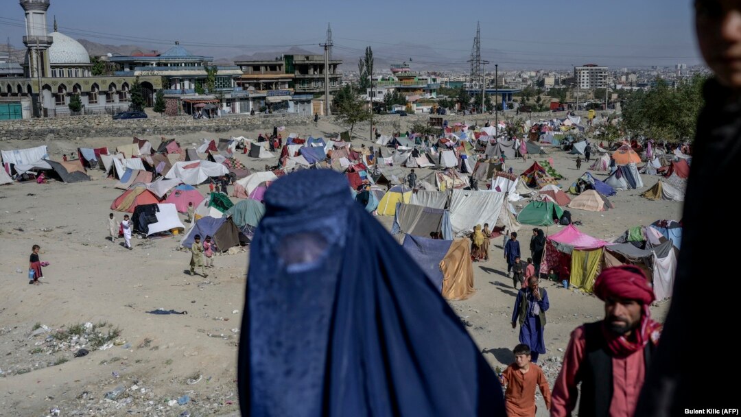 A burqa-clad woman stands by a displacement camp in Kabul on September 17.