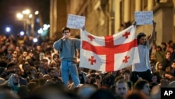 Demonstrators hold a Georgian national flag as they protest against a controversial "foreign agents" bill outside the parliament in Tbilisi on April 17.
