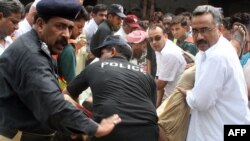 Pakistani security officials carry the dead bodies of two Christians killed in the shooting 