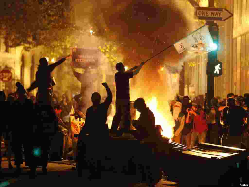 A demonstrator waves a flag as rubbish burns at the Occupy Oakland protest in Oakland, California. (Stephen Lam for Reuters) 