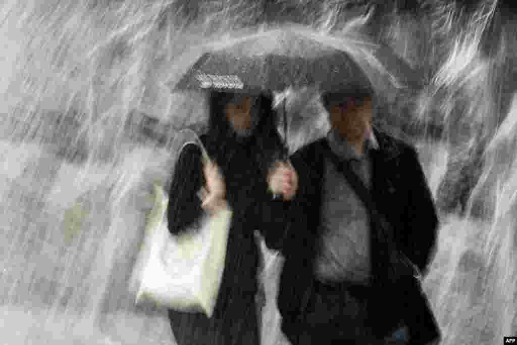 A couple tries to stay dry during a heavy storm in Moscow on May 29. At least 16 people were killed across the capital due to the violent storm. (AFP/Kirill Kudryavtsev)