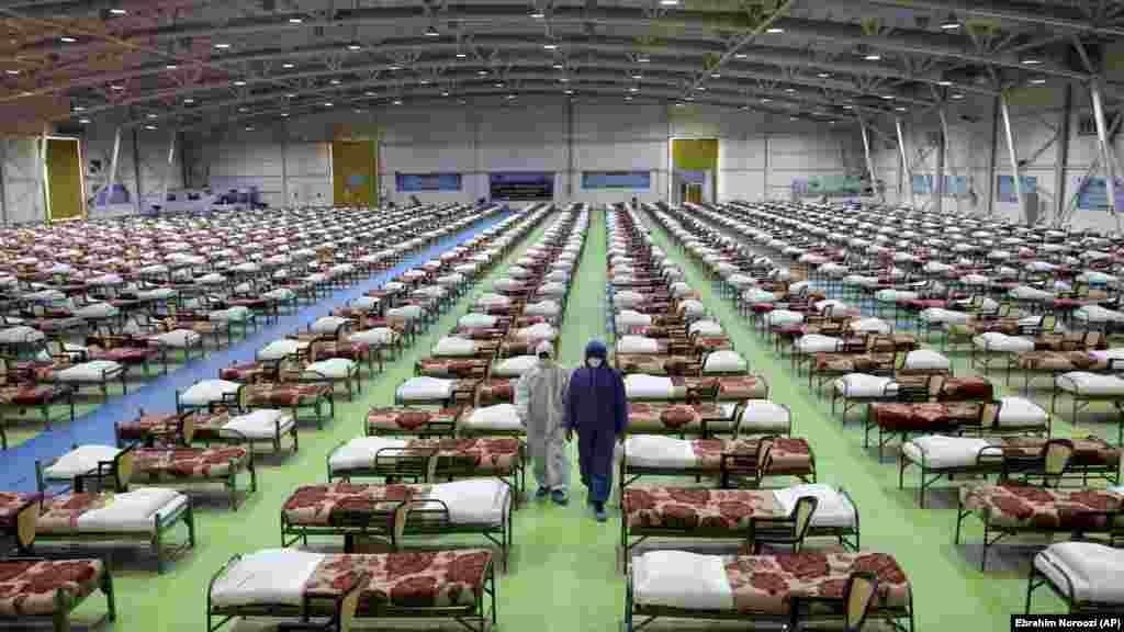 IRAN -- People in protective clothing walk past rows of beds at a temporary 2,000-bed hospital for COVID-19 coronavirus patients set up by the Iranian army at the international exhibition center in northern Tehran, March 26, 2020