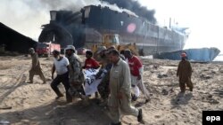 Pakistani security officials carry the body of one of the victims killed after an explosion at the Gadani ship-breaking yard on November 1.