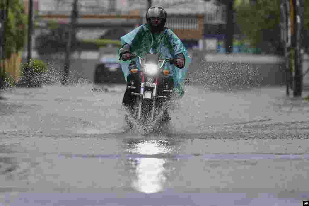 A Pakistani motorcyclist rides through a flooded road during monsoon rainfall in Rawalpindi.