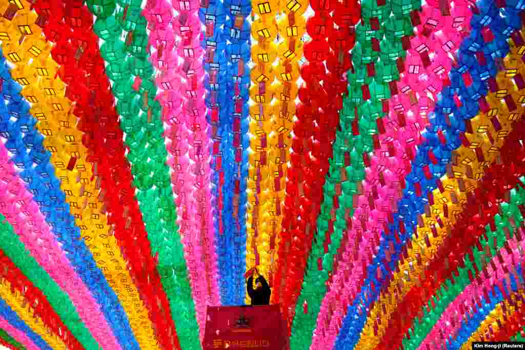 A worker wearing a protective face mask during the coronavirus outbreak attaches prayer petitions to lotus lanterns in preparation for the upcoming birthday of Buddha at a temple in Seoul. (Reuters/Kim Hong-ji)