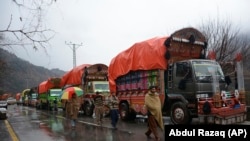 Pakistani Kashmiris walk past India-bound cargo trucks, parked as road is closed to Indian Kashmir, in the border town of Chakoti at Line of Control in Pakistani Kashmir, February 26, 2019