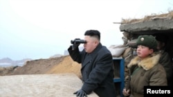 Северокорейский лидер Ким Чен Ын смотрит в биноколь в сторону Южной Кореи во время визита в военные части на границе, 7 марта 2013 года. 
