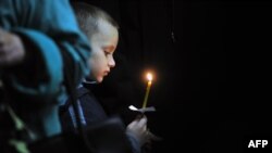 Мальчик держит свечу на акции по погибшим в авиакатастрофе в Египте. Новгород, 5 ноября 2015 года.
