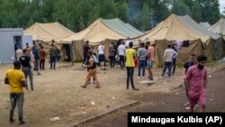 Migrants walk inside a camp that has been built to house them at a military training ground, some 38 kilometers from the Lithuanian capital, Vilnius. 