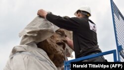 A worker covers the head of a statue of German philosopher, economist, political theorist and sociologist Karl Marx in Trier on April 13.
