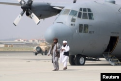 Taliban fighters walk in front of a military airplane on the day after the U.S. troops' withdrawal from Kabul airport on August 31, 2021.