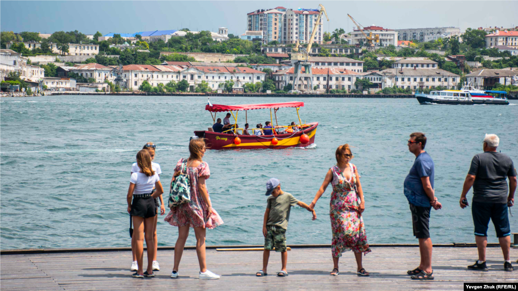 Туристи на Графській пристані в Севастополі. Графська пристань розташована в південній частині Севастoпольської бухти, на площі Нахімова. Її побудували наприкінці XVIII століття. У 1787 році до приїзду Катерини II пристань перейменували в Катерининську, а в 1925 році &ndash; в пристань III Інтернаціоналу. Лише в 1990-і роки їй повернули назву Графської на честь графа Войновича, командувача Севастопольської ескадри в 1786-1790 роках і Чорноморського флоту в 1789-1790 роках, який причалював тут, приїжджаючи зі свого хутора на Північній стороні. На сьогодні в Севастополі Графська пристань має двостороннє водне сполучення з бухтою Голландія, через яку ходять катери в Інкерман