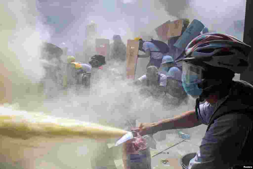 BURMA -- A protester sprays a fire extinguisher as demonstrators clash with riot police officers during a protest against the military coup in Yangon, Myanmar, February 28, 2021.