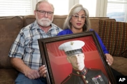 Joey și Paula Reed pozează cu un portret al fiului lor Trevor Reed, veteran al Marinei și fost prizonier rus.