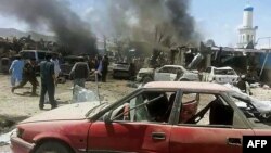 Afghan security personnel are pictured past mangled cars at the scene of a suicide attack at a busy market in Orgun district, Paktika province, July 15, 2014.