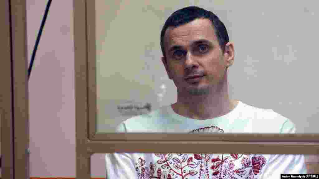 Ukrayınalı kinorejissör, qırımlı cemaat faali Oleg Sentsov Rusiyeniñ Rostov-na-Donu mahkemesinde, 2015 senesi avgustnıñ 6-sı, fotoresim müellifi &ndash; Anton Naumlük.&nbsp; Oleg Sentsov 2014 senesi mayıs ayında Rusiye uquq qoruyıcıları tarafından tutulıp, sahte terrorizm davası boyunca 20 yılğa üküm etildi. 2019 senesi sentâbrniñ 7-nde Rusiye-Ukrayına deñişüvi çerçivesinde azat etildi. Al-azırda Ukrayına Silâlı quvetleri erkânında cebede buluna.