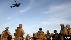 Американские морские пехотинцы смотрят на вертолет после посадки на базе Кэмп-Бастион в афганской провинции Гельменд. 23 февраля 2010 года.