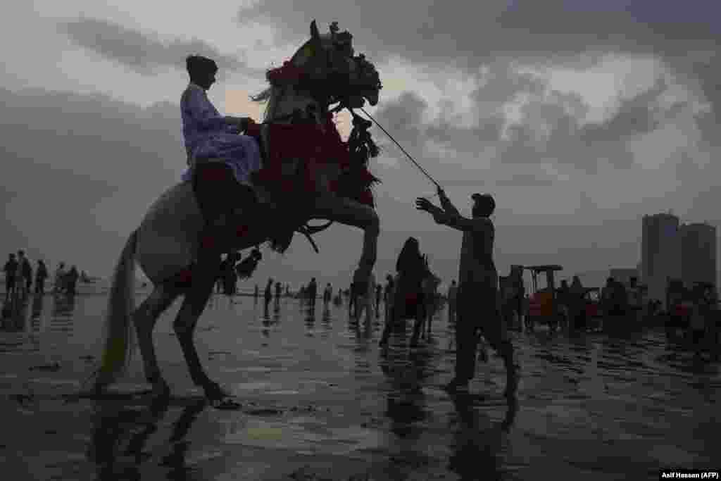 Юноша катается на лошади на пляже Клифтон в портовом городе Карачи, Пакистан